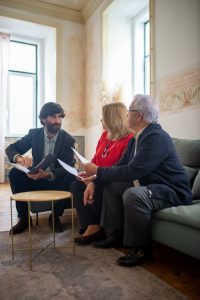 An advisor discussing financial documents with a senior couple indoors in a cozy living room setting.